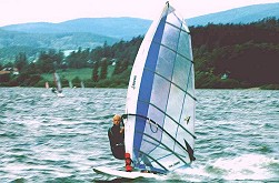 Windsurfing na Lipně, Černá v Pošumaví, vítr o síle přibližně 8 m/s, v popředí jede Martin Jelínek s plachtou Arrows Tomahawk 6.6m2 a plovákem Fanatic UltraRay282